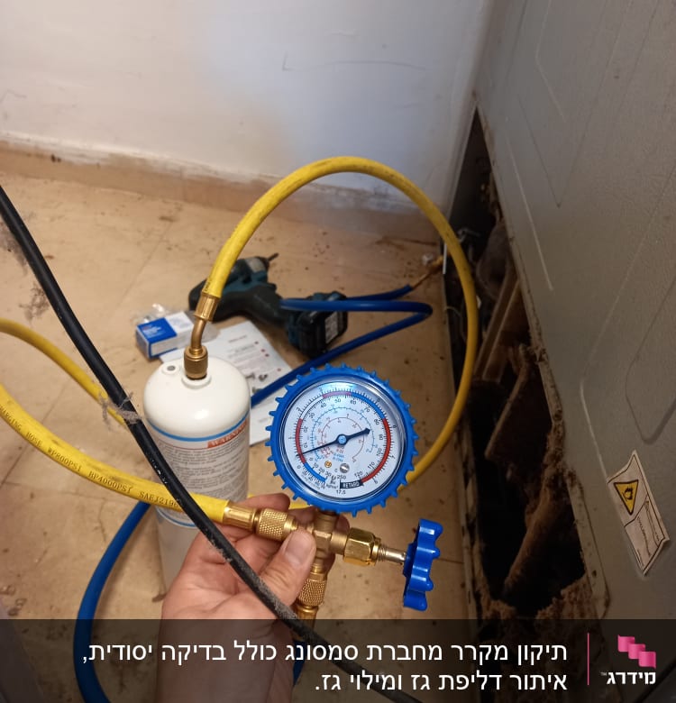 מד לחץ כחול מחובר לצינור צהוב ליד מקרר